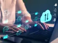 Ręce na klawiaturze laptopa, wizualizacja przepływu danych do chmury. Ikony folderów i dokumentów łączą się z chmurą, symbolizując zarządzanie plikami i serwer ftp.