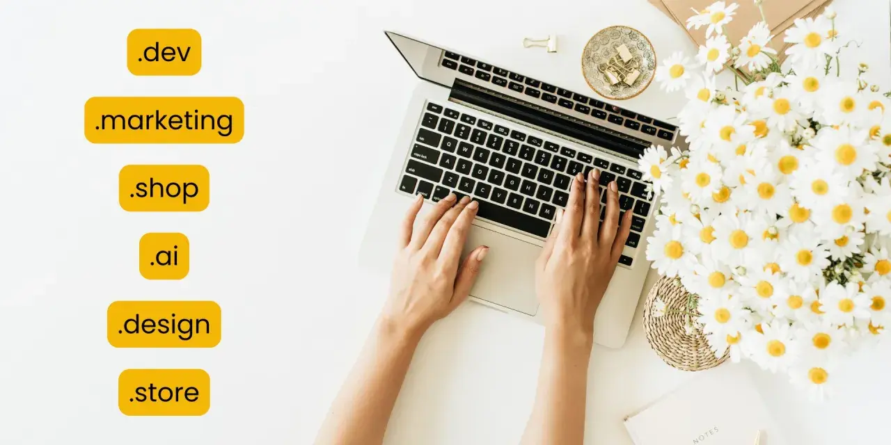 Kobieta pisze na laptopie, obok bukiet margaretek. Widoczne są różne rozszerzenia domen, np. .dev, .marketing, .shop, .ai, .design, .store.