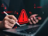 Ręce nad laptopem i telefonem, otoczone czerwonymi ostrzeżeniami i ikonami kłódki. To jakby tracker kto to, próbuje się włamać.