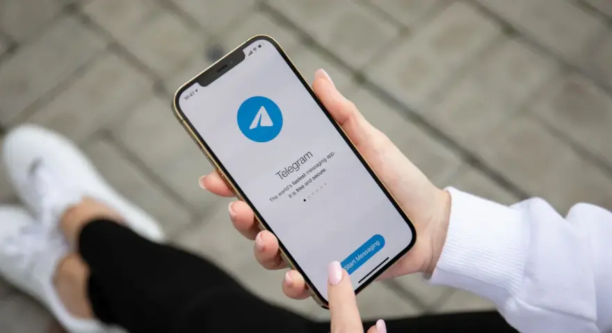 Dłoń trzyma smartfon z otwartą aplikacją Telegram. To szybka i bezpieczna apka do wysyłania wiadomości.