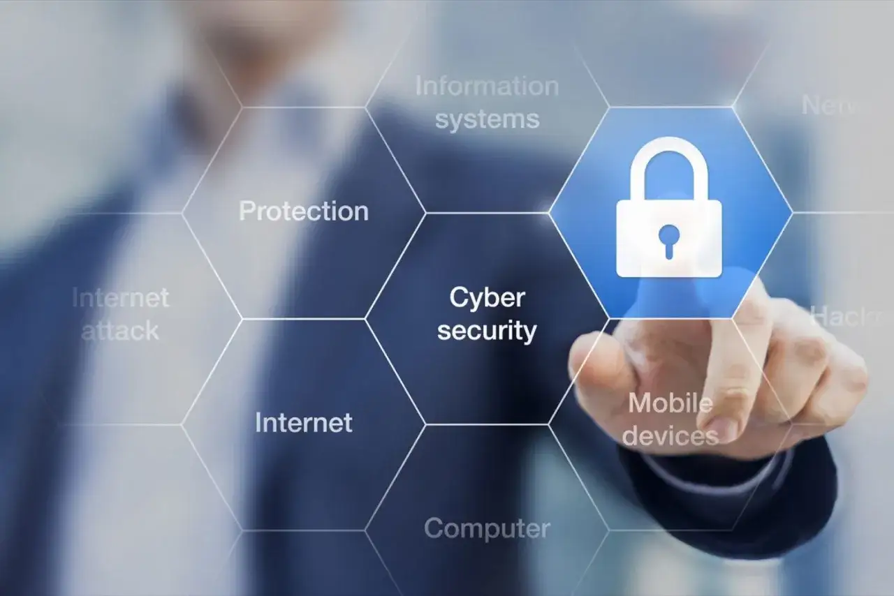 Palec wskazuje na ikonę kłódki w centrum, symbolizującą cyberbezpieczeństwo. Wokół niej widnieją hasła: 